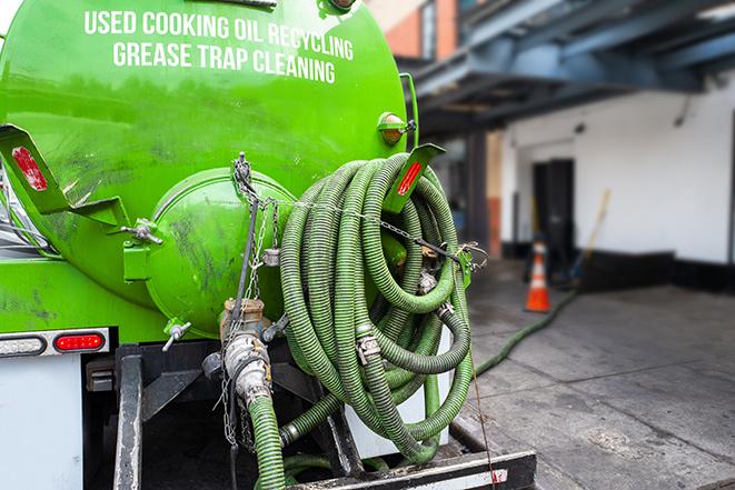 a professional plumber using a pump to empty a grease trap in Greenbush, WI